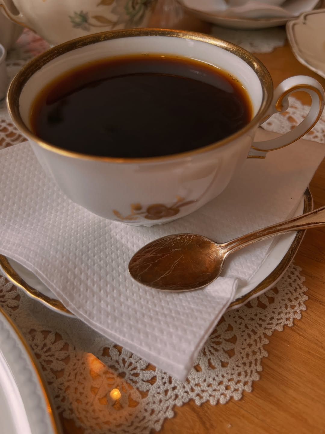 Porcelanowa filiżanka kawy ze złotym brzegiem na koronkowym obrusie